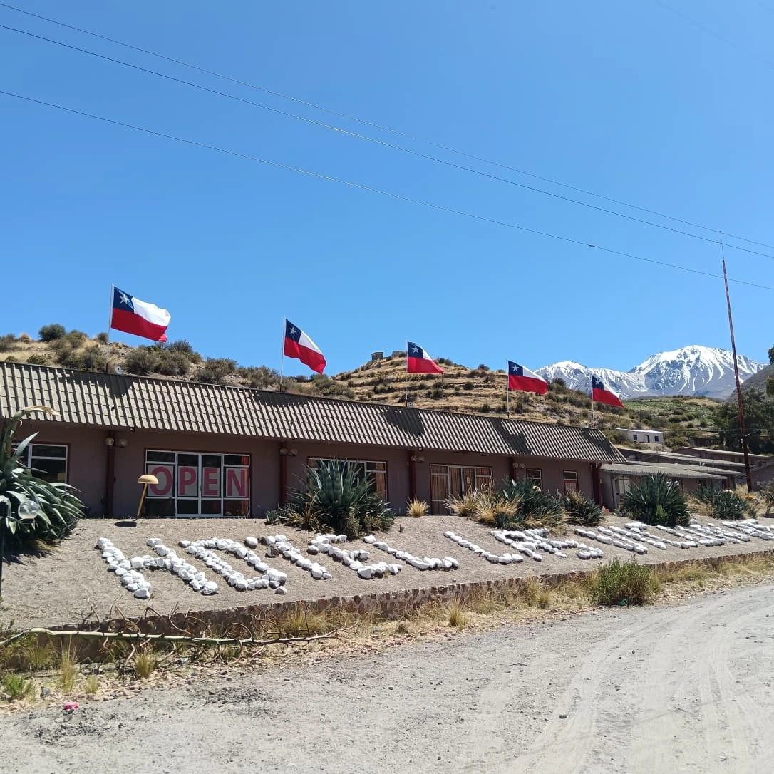 Fachada de Hotel Las Vicuñas con banderas chilenas y montañas al fondo